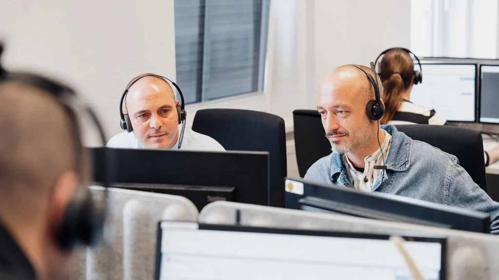Mitarbeitende mit Headset am Arbeitsplatz