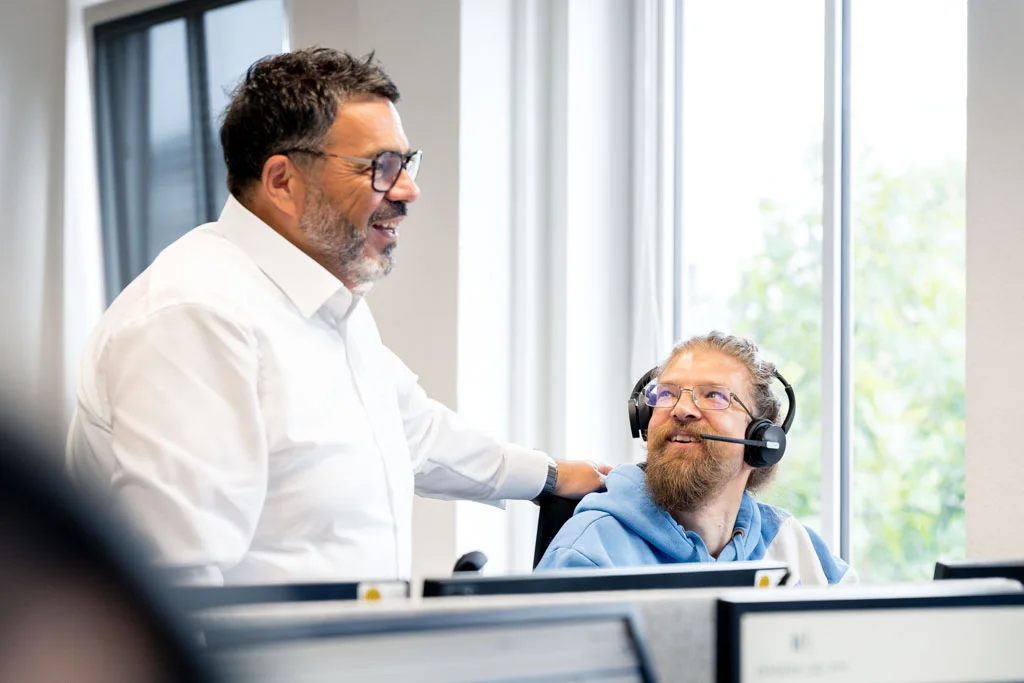 Teamleiter im Gespräch mit einem Mitarbeiter im Telefonverkauf